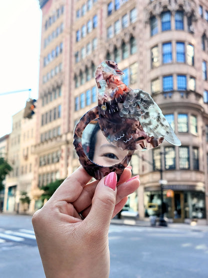 Hand holding the open pigeon compact mirror on a city street