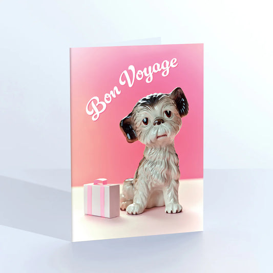 Ornament card: a fluffy dog figurine beside a pink gift box, with 'Bon voyage'