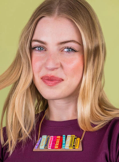 Smiling woman in a plum top wearing the bookshelf necklace