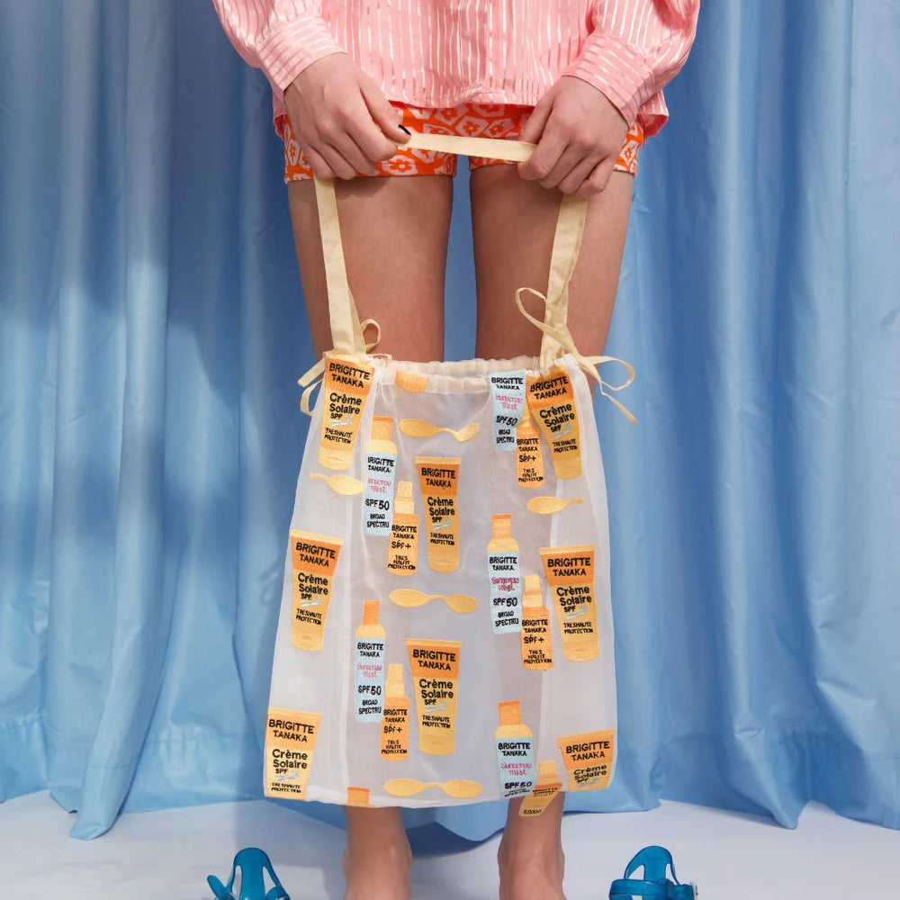 Sun Creme bag held up in front of blue curtains