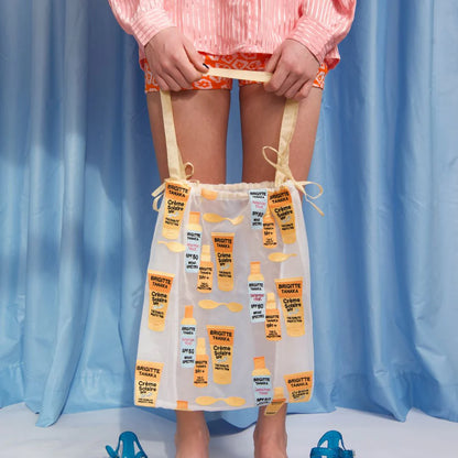 Sun Creme bag held up in front of blue curtains