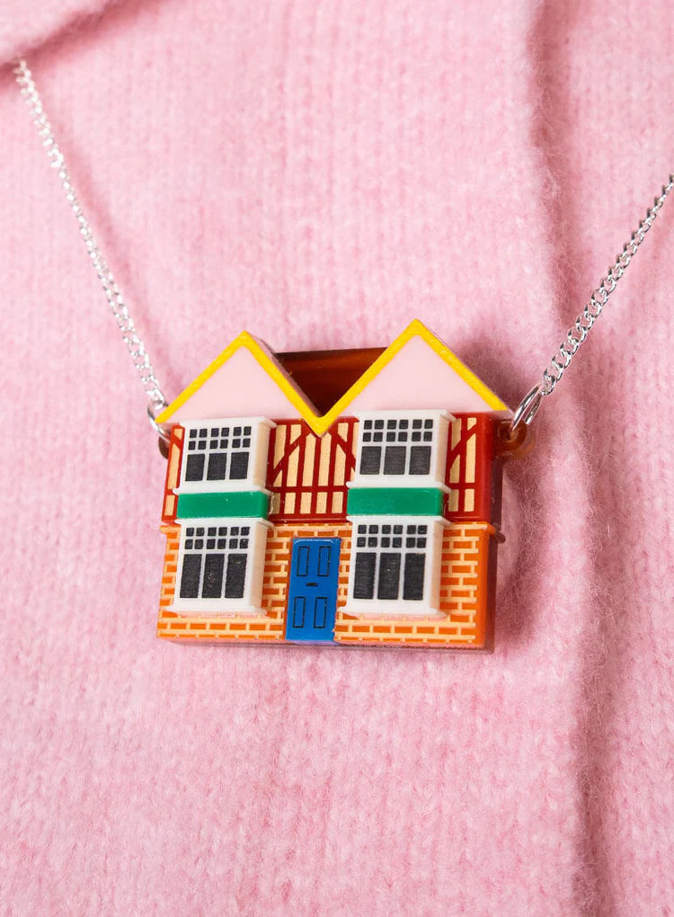 Dolls' house necklace worn on a pink knit