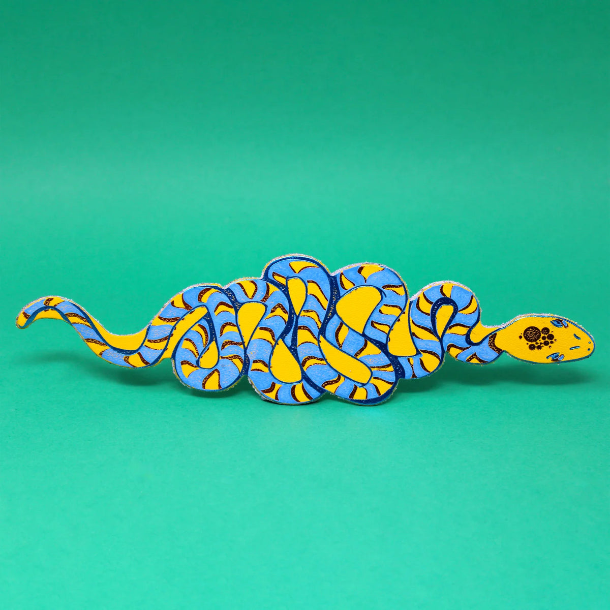 Yellow and blue coiled snake leather bookmark on a green background