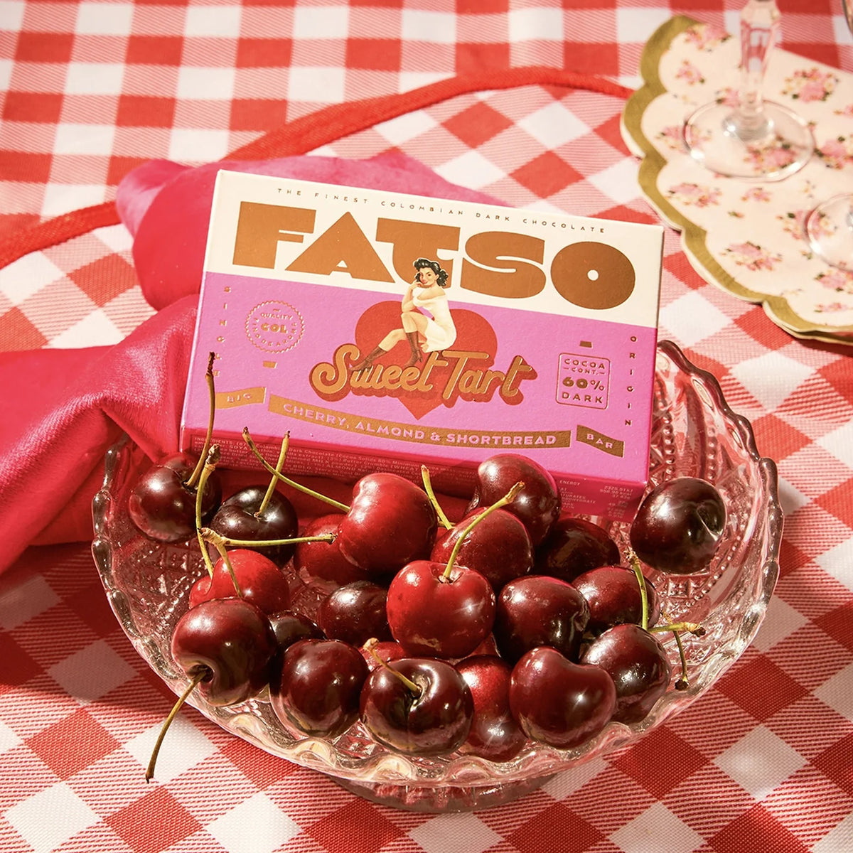 Sweet Tart chocolate beside a bowl of cherries on a red check tablecloth