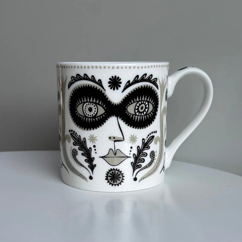 Lush Designs Masquerade mug: a black and gold face with a mask and patterned leaves