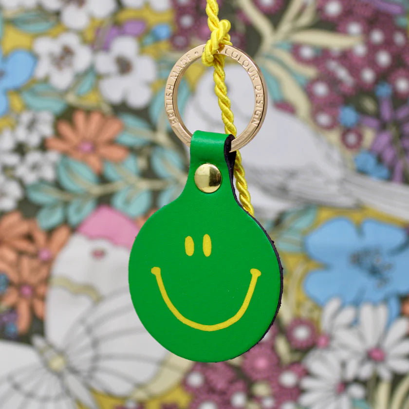 Ark green leather smiley face key fob against a floral pattern
