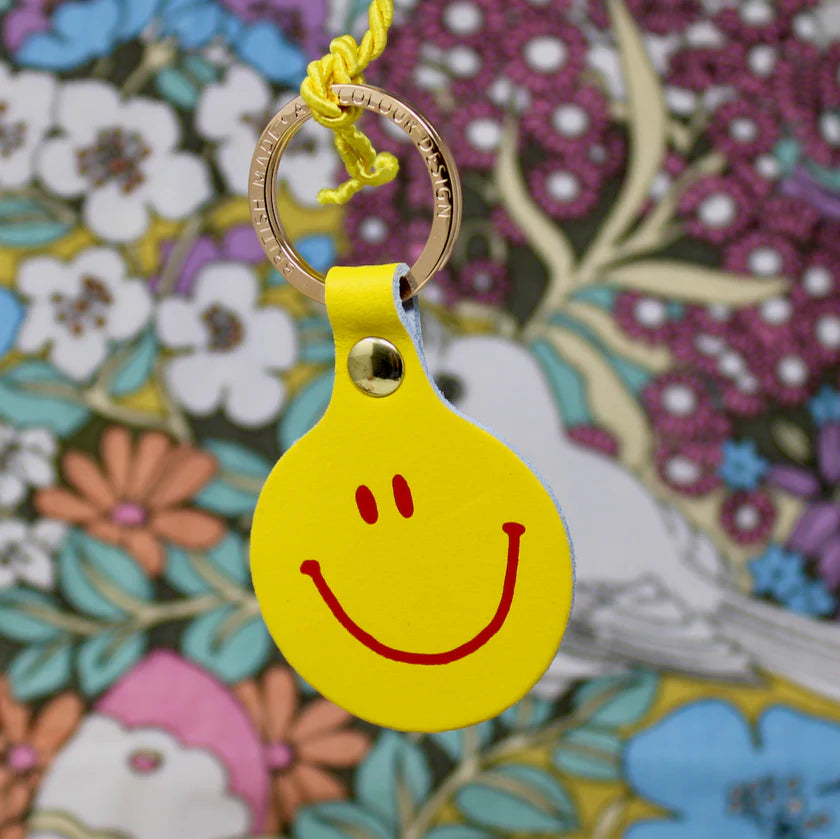 Ark yellow leather smiley face key fob against a floral pattern