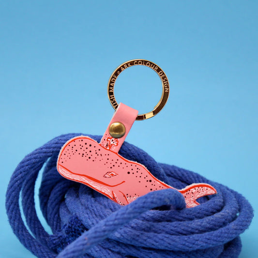 Pink leather humpback whale key fob on a gold ring, resting on blue rope