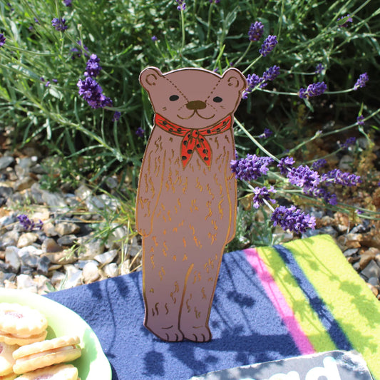 Ark bear bookmark in dusty pink with a red neckerchief, standing outdoors