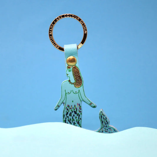 Ark blue mermaid leather key ring with a gold ring, against a blue background