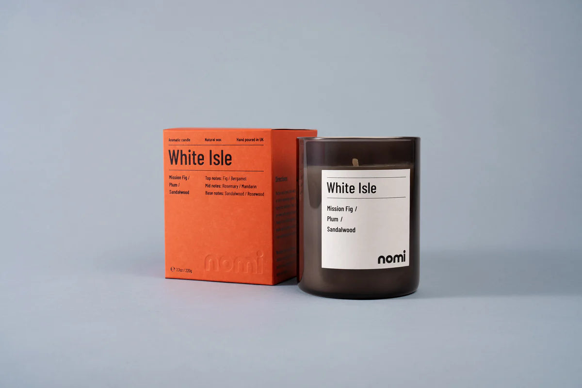 Nomi White Isle scented candle in an amber jar beside its orange box
