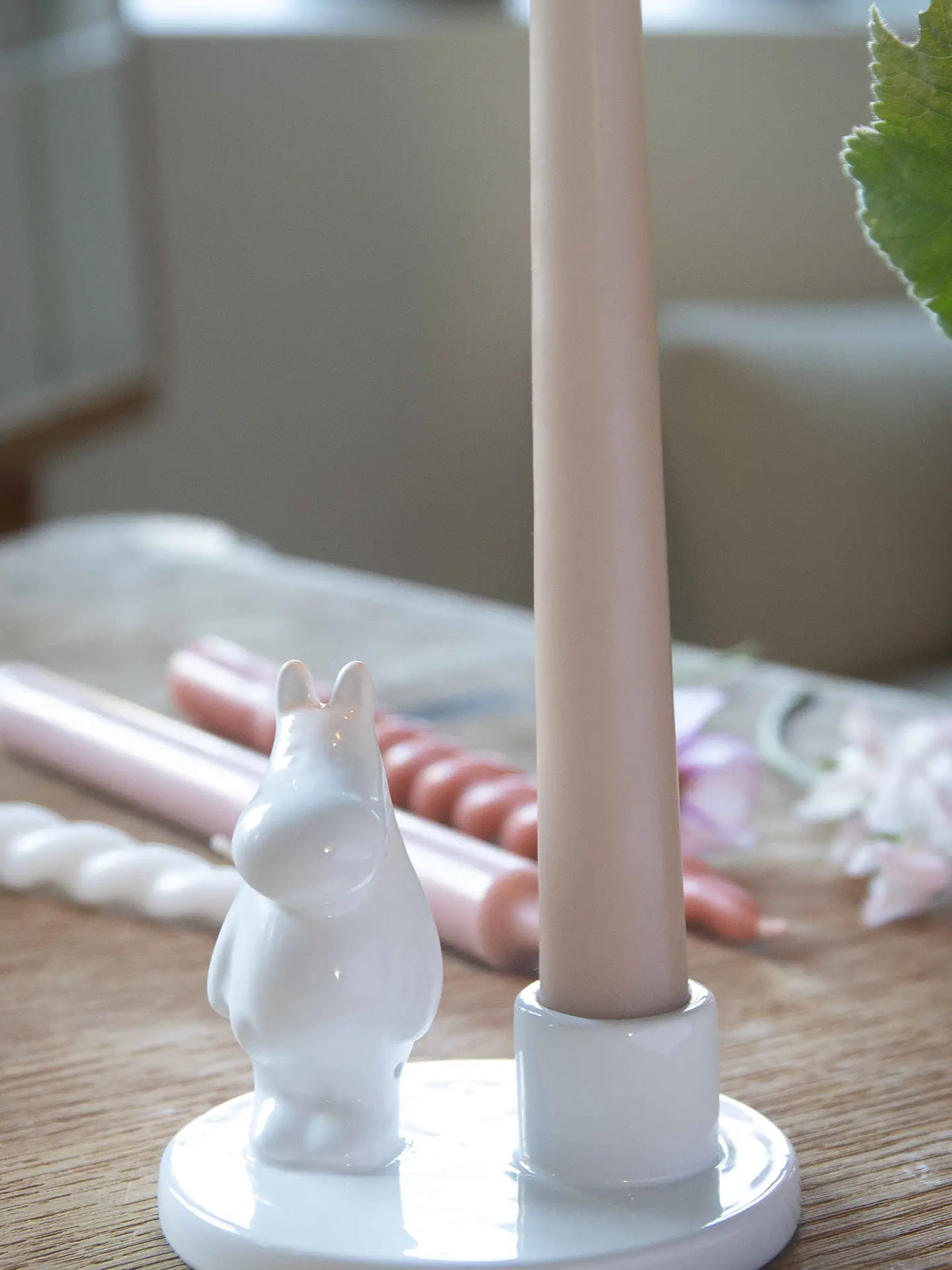 Moomin candle holder with a pink candle on a table