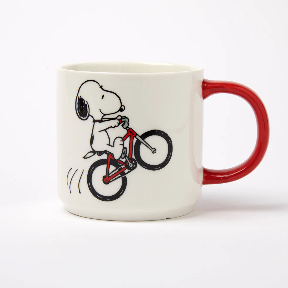 White mug with a red handle and Snoopy doing a wheelie on a bike
