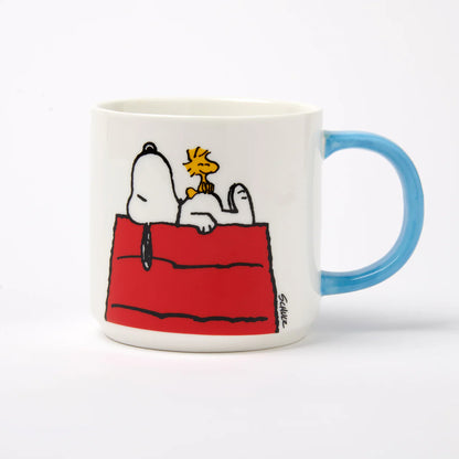 White mug with a blue handle and Snoopy on his kennel with Woodstock