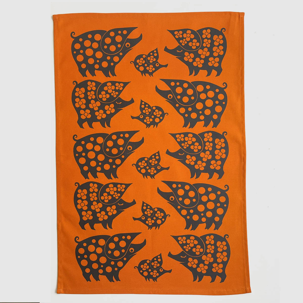 Magpie x Hornsea orange tea towel with a pattern of black piggy families