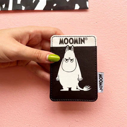 Hand holding the black Moomin card holder with an angry Moomintroll