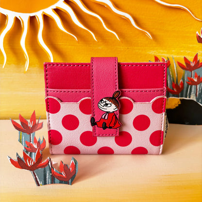 Little My polka dot wallet in front of a painted desert scene with a sun