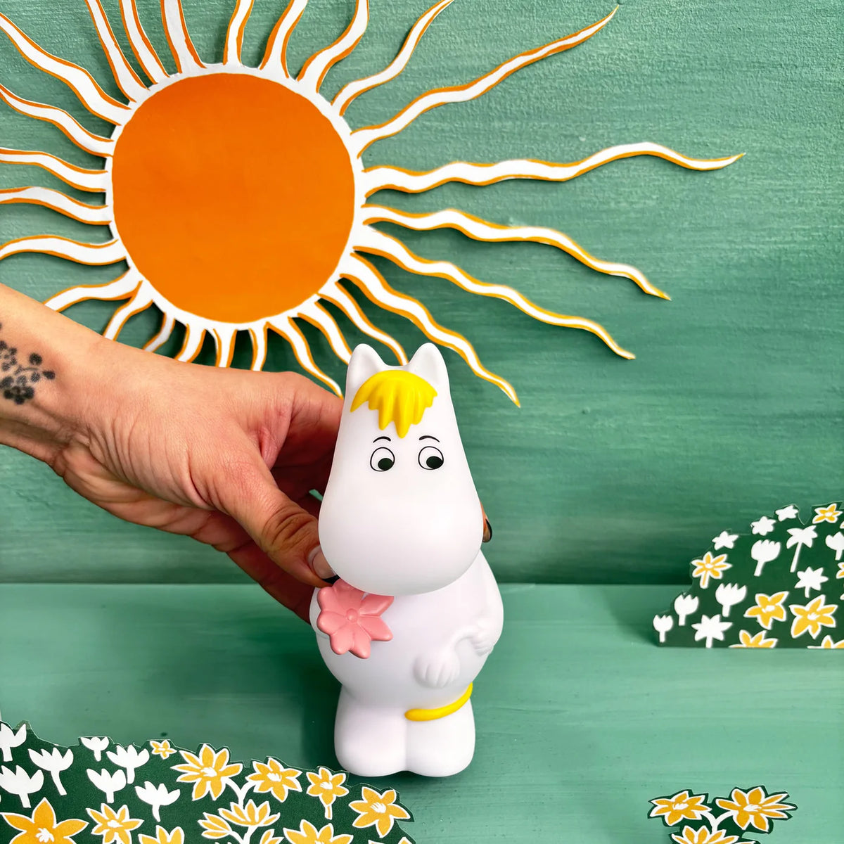 Hand holding the Snorkmaiden light against a painted sun