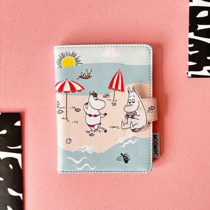 Moomin beach passport holder: Moomins under a red and white parasol on the beach, on pink