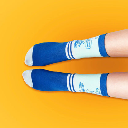 Feet wearing the Moomin Excellent Idea socks on yellow