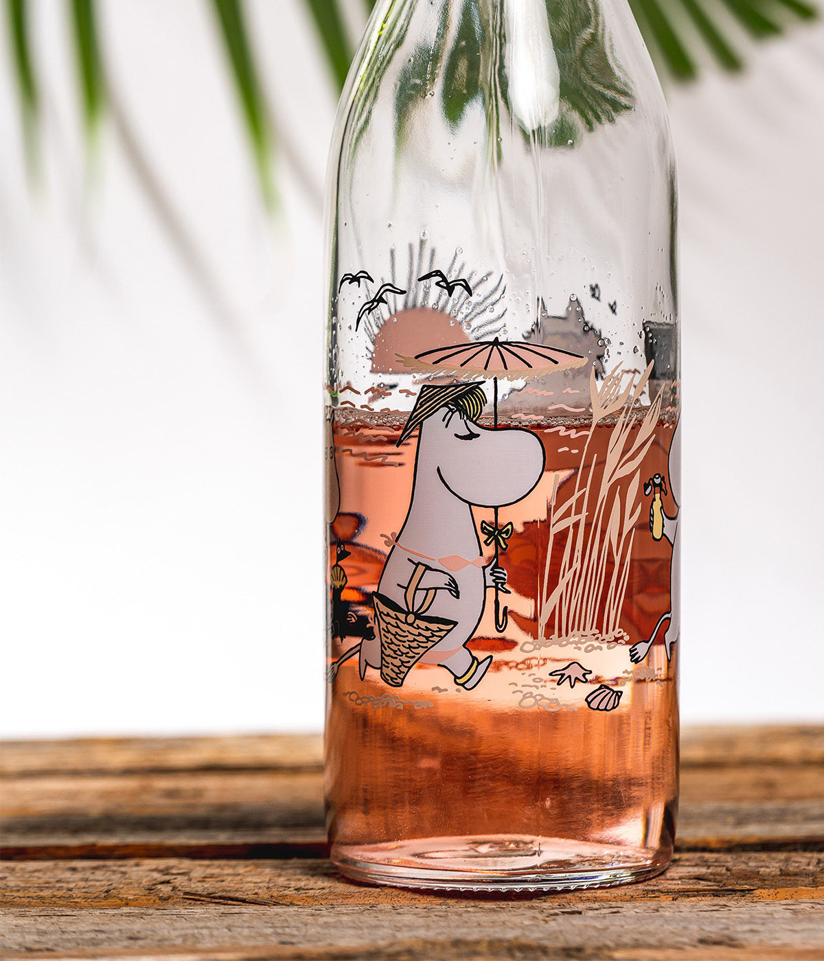 Moomin beach bottle filled with pink drink on a wooden table