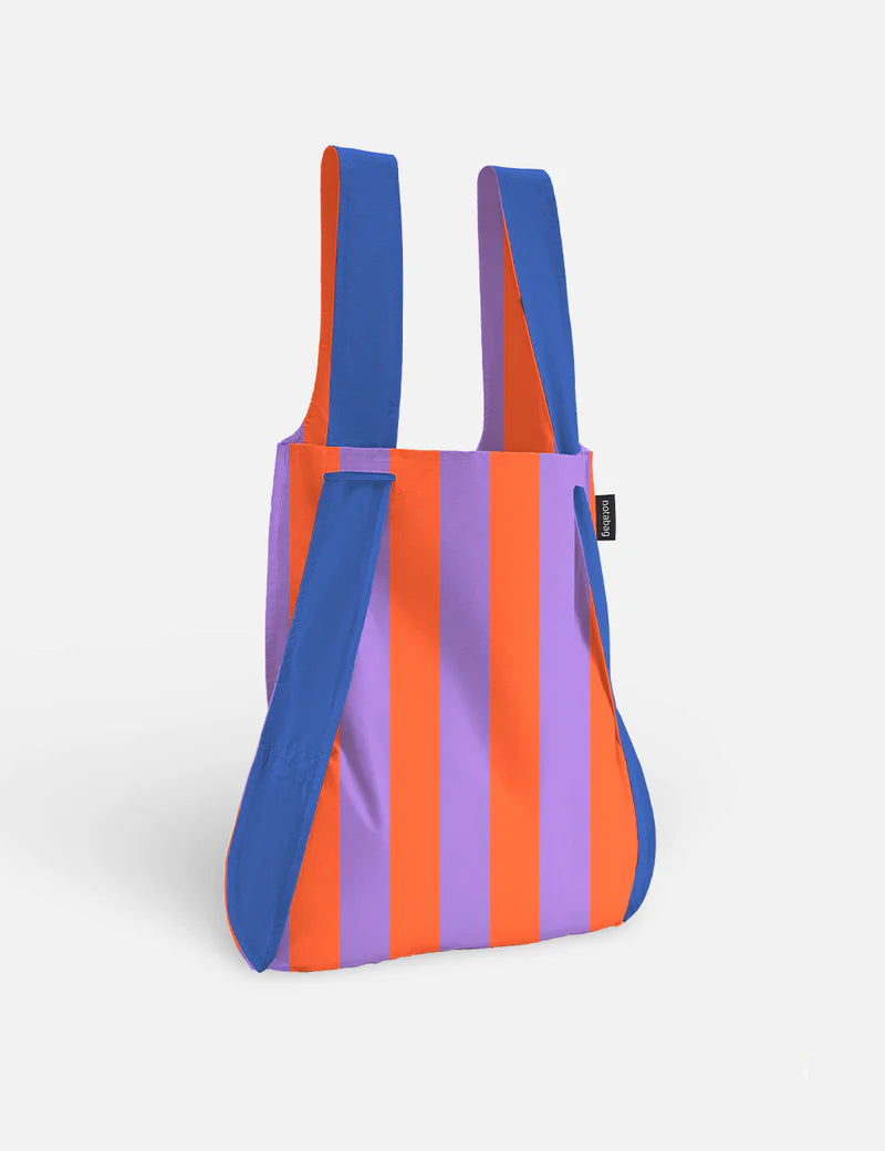 Notabag in red and lilac stripes with blue straps, worn as a backpack shape