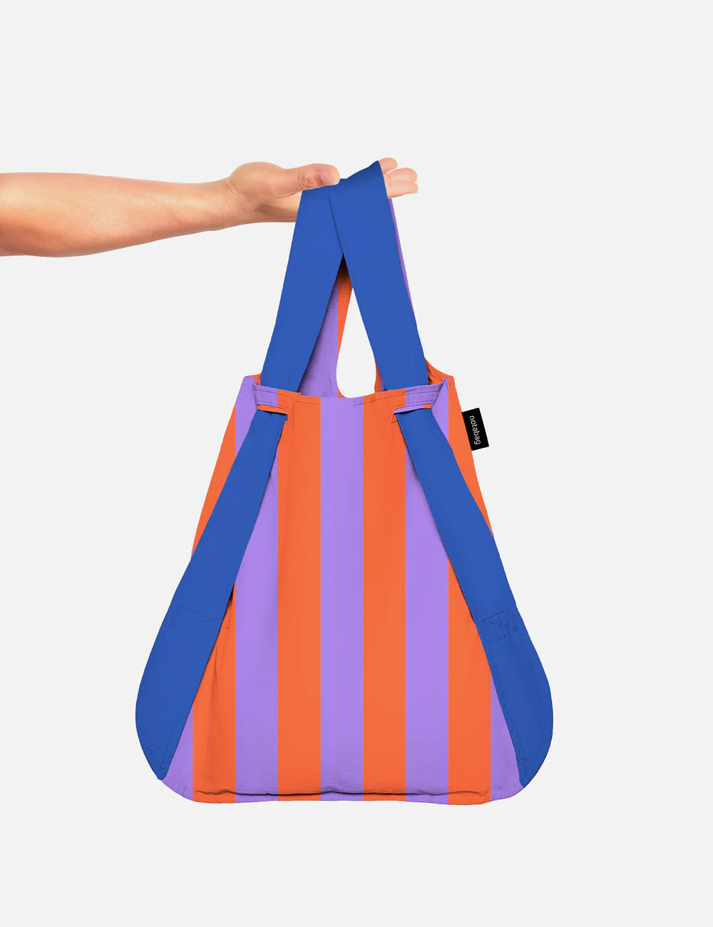 Hand holding the striped Notabag by its blue backpack straps