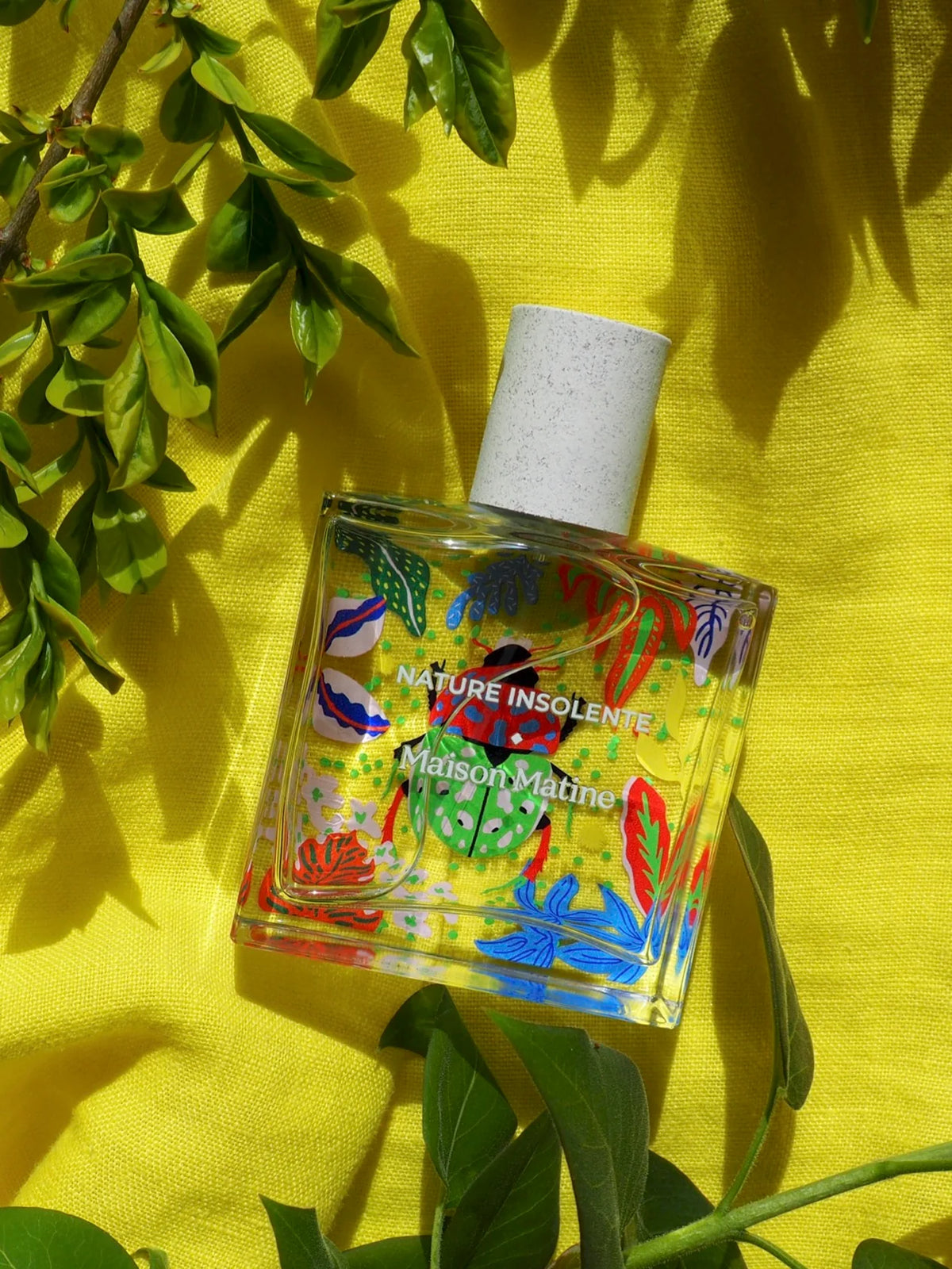 Nature Insolente perfume on yellow fabric among leaves