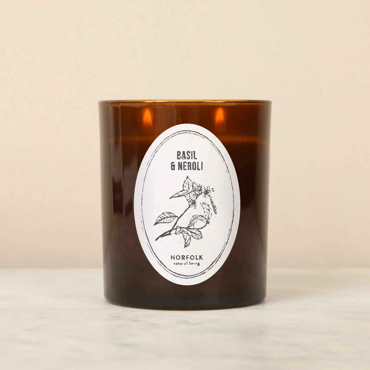 Norfolk Natural Living Basil & Neroli candle in an amber glass jar with an oval botanical label