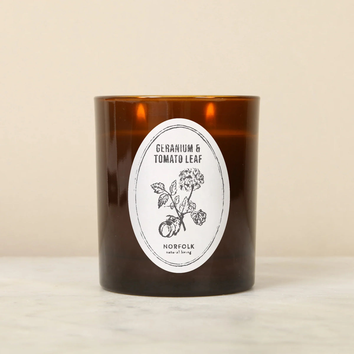Norfolk Natural Living Geranium & Tomato Leaf candle in an amber glass jar with an oval botanical label