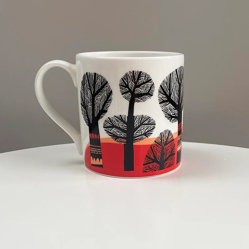 Lush Designs Tree mug: black trees against an orange and red sunset band