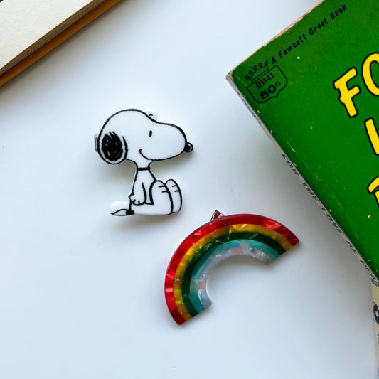 Peanuts hair clips: a Snoopy clip and a rainbow clip on a white table