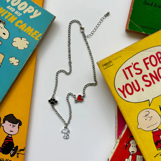 Peanuts Snoopy charm necklace with a red heart and paw print among Peanuts books