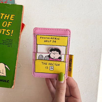 Hand holding the Lucy card holder next to a Peanuts comic book