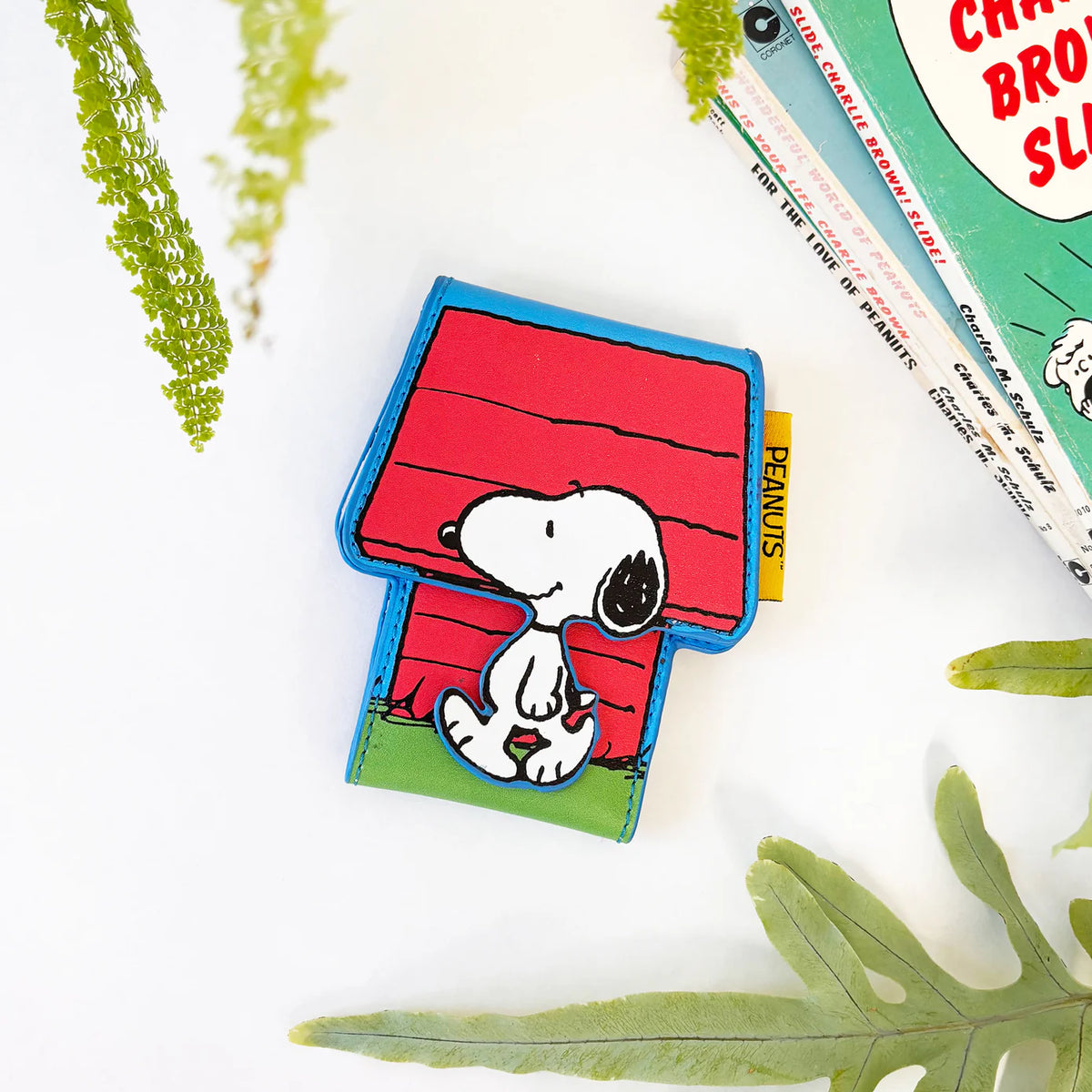Doghouse card holder on a white table with a Peanuts book