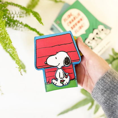 Hand holding the doghouse card holder near plants