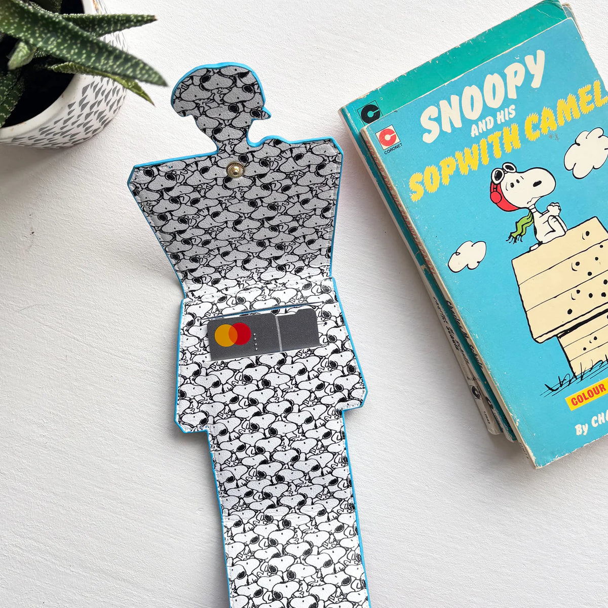 Doghouse card holder opened to show the Snoopy-print lining and a bank card