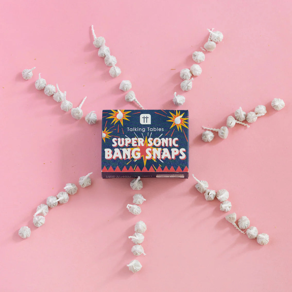 Super Sonic Bang Snaps box surrounded by bang snaps arranged like fireworks on pink