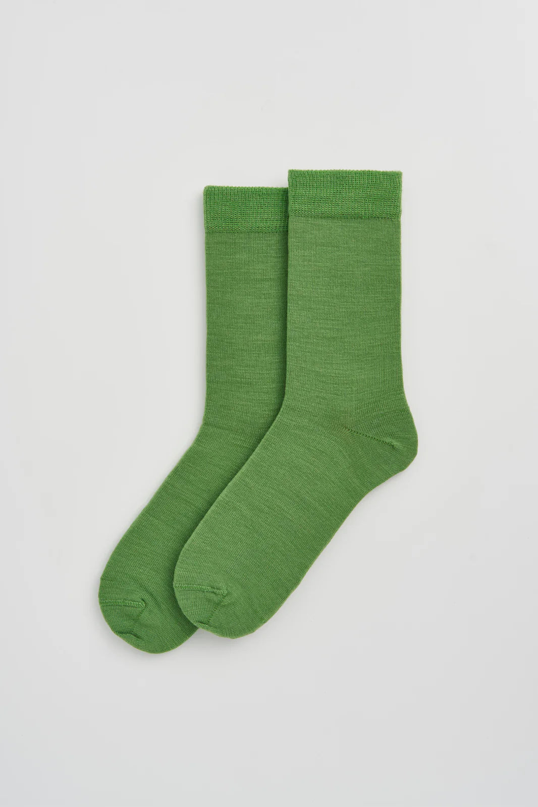 Pair of grass green calf-length merino socks laid flat