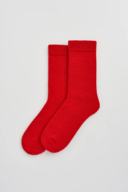 Pair of red calf-length merino socks laid flat
