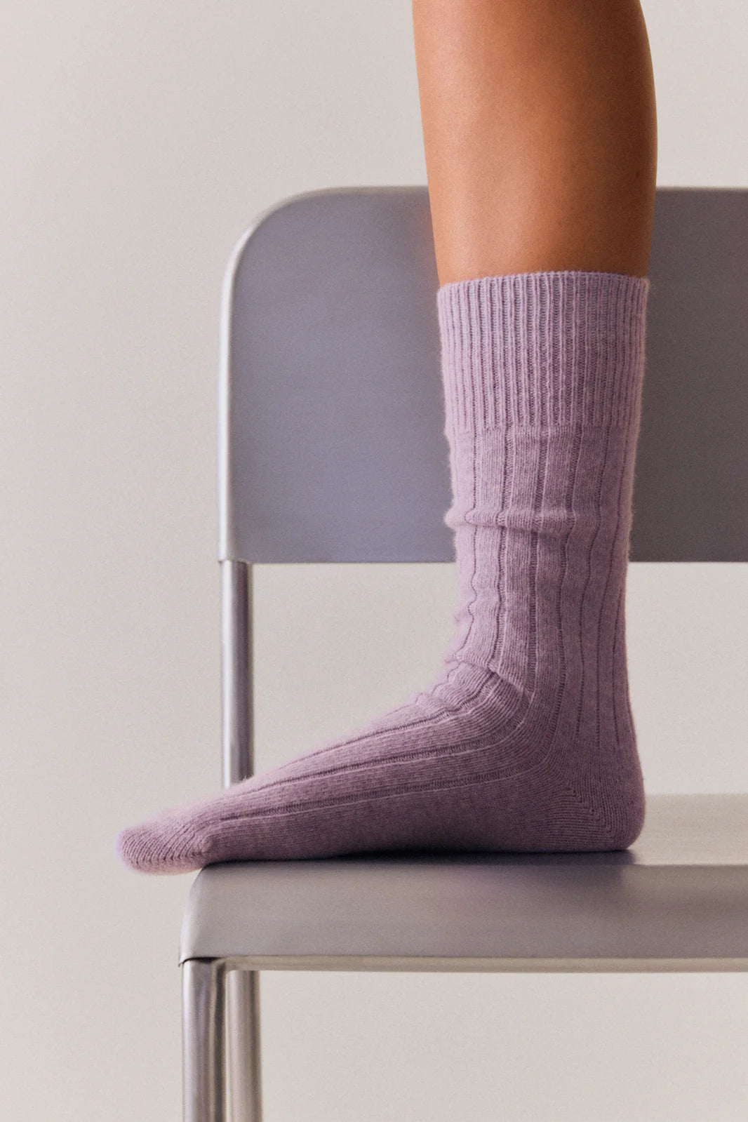 Foot in a parma violet bed sock resting on a chair