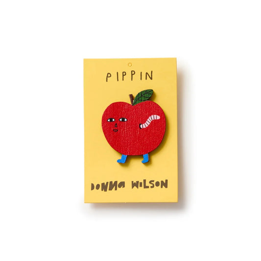 Donna Wilson Pippin pin badge: a red apple with a worm, on its yellow card