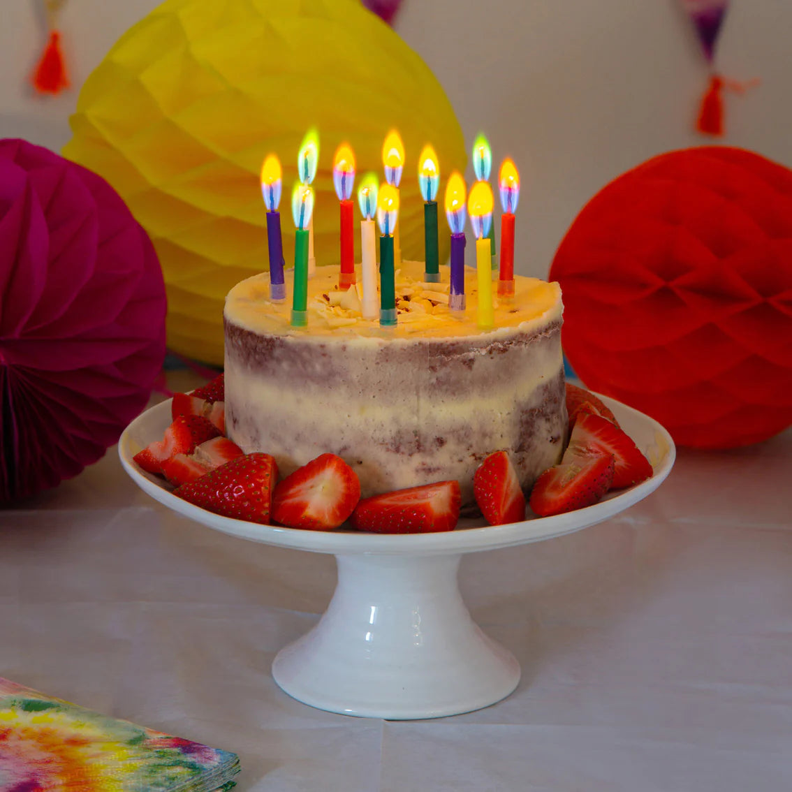 Layered cake topped with lit birthday candles burning with coloured flames