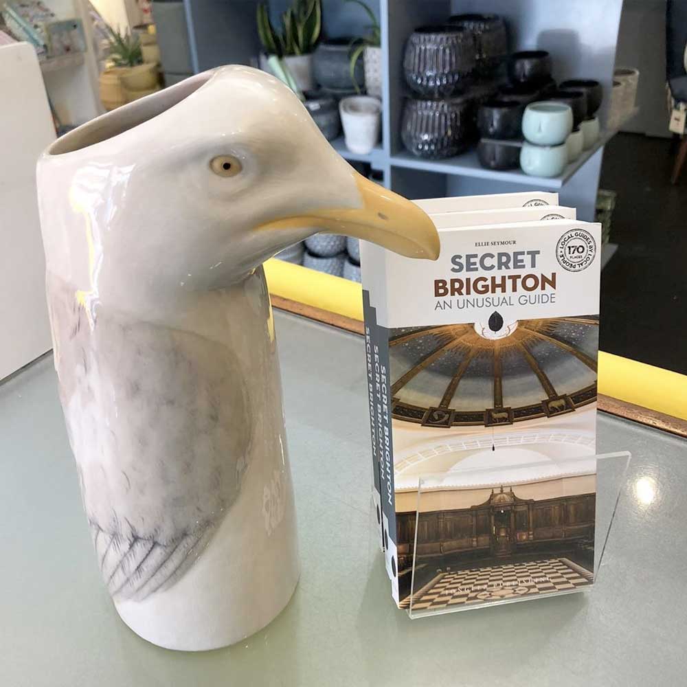 Herring gull vase on a shop counter beside a Secret Brighton guidebook