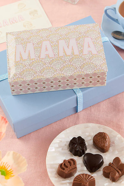 The Chocolate Gift Co Mama chocolate truffle tin on a blue box beside chocolates