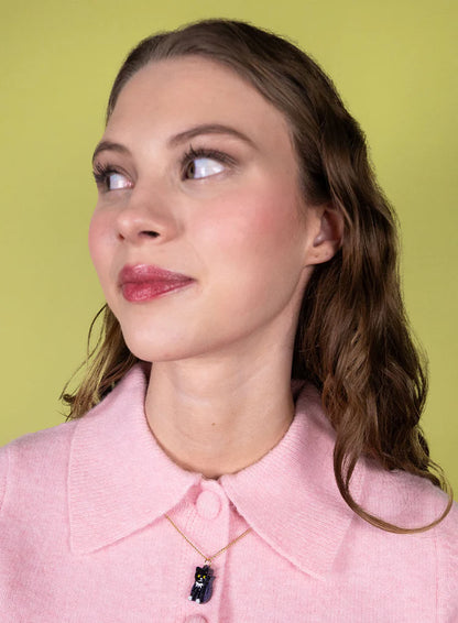 Woman in a pink cardigan wearing the toy cat pendant