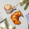 Croissant bauble on a table beside a cappuccino