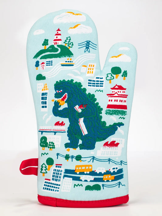 Blue Q oven mitt: a green dinosaur eating cookies in a city