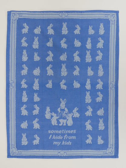 Unfolded tea towel with rows of rabbits and 'Sometimes I hide from my kids'