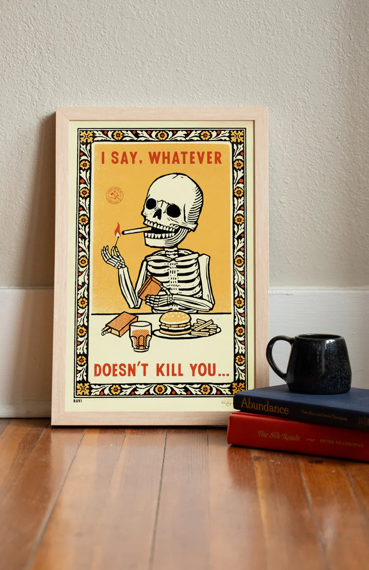 Whatever Doesn't Kill You print leaning on a wall by books and a mug